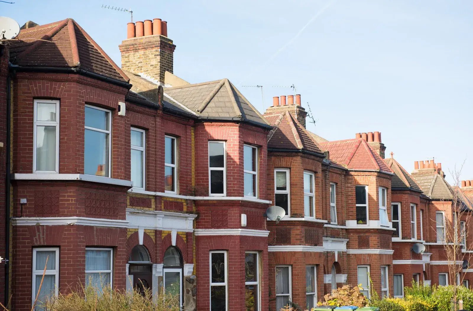 Street view of traditional red‑brick houses with chimneys and front gardens